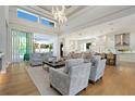 Open-concept living room with light wood floors, plush seating, high ceilings, and seamless flow to outdoor spaces at 5103 Windward Ave, Sarasota, FL 34242