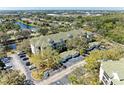 Aerial view shows parking and condo exterior, surrounded by lush trees and landscaping near a pond at 5160 Northridge Rd # 302, Sarasota, FL 34238