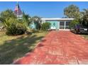 Quaint turquoise home with an American flag, tropical plants, and a red brick driveway at 540 Palmetto Ne Dr, Port Charlotte, FL 33952