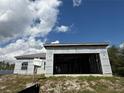 Garage opening on a one-story unfinished home with a metal roof shown under a cloudy, bright, blue sky at 6970 Beckwith Ave, North Port, FL 34291