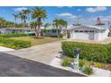 Inviting home with manicured lawn, mature palm trees, and a paved driveway leading to an attached garage at 7337 Starfish Dr, Sarasota, FL 34231