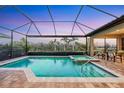 Inviting pool with spa in screened-in lanai, surrounded by lush landscaping and brick pavers at 7469 Seacroft Cv, Lakewood Ranch, FL 34202