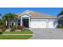 Beautiful single-story home with a three-car garage, paver driveway, and lush landscaping at 813 Tailwind Pl, Sarasota, FL 34240