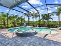 Screened-in lanai featuring a private in-ground pool and spa surrounded by lush landscaping and a brick paver deck at 813 Tailwind Pl, Sarasota, FL 34240