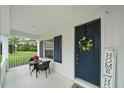 Cozy front porch area with seating, white railing, dark shutters and a navy front door at 12225 Whisper Lake Dr, Bradenton, FL 34211