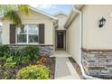 Close-up of the front door showcasing stone accents, a decorative light fixture and colorful landscaping at 13718 Woodbridge Ter, Lakewood Ranch, FL 34211