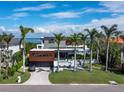 Beautiful, modern multi-level home featuring manicured lawn, palm trees and a private drive leading to an attached garage at 1580 Harbor Cay Ln, Longboat Key, FL 34228