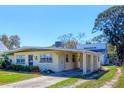 A cozy single-story house with a convenient carport is bathed in sunlight against a bright blue sky at 2564 Wood St, Sarasota, FL 34237