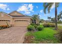 A well-maintained two-car garage home with a brick paved driveway and lush landscaping at 4331 Turnberry Cir, North Port, FL 34288