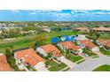Aerial view of a home with a tile roof, nicely landscaped yard, and a pond on a golf course in the background at 4909 Clubview E Ct, Bradenton, FL 34203