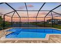 Screened-in pool with scenic waterfront views, ideal for relaxation and entertaining under the setting sun at 5822 Title Row Dr, Bradenton, FL 34210