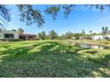 Scenic backyard featuring a lush green lawn, mature trees, and tranquil waterfront views, a perfect retreat at 622 Spring Lakes Blvd, Bradenton, FL 34210