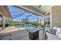 Enclosed pool area featuring a screened-in pool, outdoor furniture, and waterfront view at 6621 The Masters Ave, Lakewood Ranch, FL 34202
