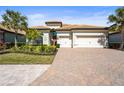 Beautiful home with a three-car garage, paver driveway, lush landscaping, and a terracotta roof at 7036 Whittlebury Trl, Lakewood Ranch, FL 34202