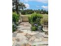 Scenic stone pathway leading to an iron gate, surrounded by lush greenery and colorful flowers at 10157 Sunburst Ct, Spring Hill, FL 34608