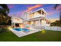 Rear exterior view showcasing a pool, hot tub, outdoor kitchen, and putting green at 112 50Th St, Holmes Beach, FL 34217