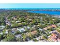 Expansive aerial view shows this property with mature trees surrounded by water and coastal cityscape at 1610 S Lake Shore Dr, Sarasota, FL 34231