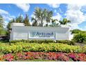Avelina Wellen Park community entrance featuring a decorative sign, lush landscaping, and beautiful flower beds at 18736 Toulon Ct, Venice, FL 34293