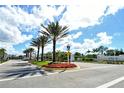Avelina Wellen Park community entrance with palm trees, manicured lawns, and decorative flower beds at 18736 Toulon Ct, Venice, FL 34293