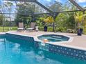 Inviting screened-in pool with a built-in spa, tiled trim, and poolside seating at 201 Eaglenook Way, Osprey, FL 34229