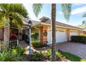 Charming home exterior showcasing a brick driveway, decorative foliage, and attached garage at 2123 Lynx Run, North Port, FL 34288