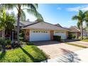 Inviting home exterior with a brick driveway, lush green lawn, and well-maintained landscaping at 2123 Lynx Run, North Port, FL 34288