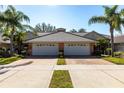 Villa-style home with a well-manicured lawn, palm trees, and a brick driveway, offering a serene setting at 2123 Lynx Run, North Port, FL 34288