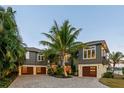 Stunning multi-level home featuring private garages, lush landscaping, and an inviting facade at 242 Oak Ave, Anna Maria, FL 34216