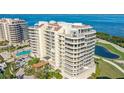 Stunning exterior view of a waterfront condo featuring a pool, parking and beautifully manicured landscaping at 3040 Grand Bay Blvd # 234, Longboat Key, FL 34228