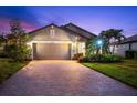 Charming single-Gathering home displaying a two-car garage, brick driveway, and landscaped front yard at twilight at 6912 Gosport Cv, Bradenton, FL 34202