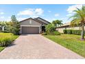 Charming single-Gathering home displaying a two-car garage, brick driveway, and landscaped front yard at 6912 Gosport Cv, Bradenton, FL 34202