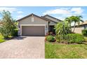 Charming single-Gathering home displaying a two-car garage, brick driveway, and landscaped front yard at 6912 Gosport Cv, Bradenton, FL 34202