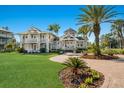 Stunning two-story home with a manicured lawn, brick pathway, and lush tropical landscaping at 766 Bayshore Dr, Terra Ceia, FL 34250