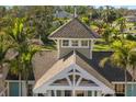 View of house roof with a turret design and white trim detailing, surrounded by lush greenery and palm trees at 766 Bayshore Dr, Terra Ceia, FL 34250