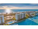 Exterior of a condo building on the water with lush landscaping, a pool, and tennis court at 9393 Midnight Pass Rd # 506, Sarasota, FL 34242