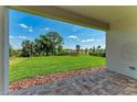 A covered patio with a view of a well-maintained lawn, garden, and a clear blue sky beyond at 995 Waterline Ct, Sarasota, FL 34240