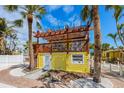Charming yellow home featuring a pergola-covered deck and tropical landscaping at 110 Oak Ave # A, Anna Maria, FL 34216