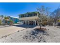Stilt home featuring a large driveway and an enclosed lower level providing ample parking and storage space at 313 Magnolia Ave, Anna Maria, FL 34216