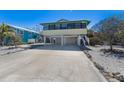 Stilt home featuring a large driveway and an enclosed lower level providing ample parking and storage space at 313 Magnolia Ave, Anna Maria, FL 34216