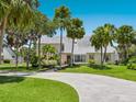 Two-story home featuring a circular drive, mature palm trees, and lush landscaping at 3648 Beneva Oaks Blvd, Sarasota, FL 34238