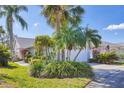 Well-maintained home featuring mature palm trees and vibrant landscaping in the front yard at 5608 Country Club Way # 5608, Sarasota, FL 34243