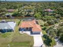 Gorgeous aerial view of a waterfront home with a red tile roof, lush landscaping, and community canal access at 108 Mccabe St, Port Charlotte, FL 33953