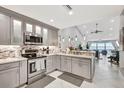 Open concept kitchen featuring stainless steel appliances and modern gray cabinetry and views to the living room and water at 1602 Stickney Point Rd # 404, Sarasota, FL 34231