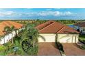 Exterior elevation of home featuring a brick driveway, two-car garage and meticulously landscaped yard at 24068 Canterwood Way, Venice, FL 34293
