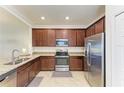 Modern kitchen features stainless steel appliances, granite countertops and dark wood cabinets at 24068 Canterwood Way, Venice, FL 34293