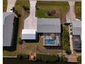 Aerial view of a home featuring a pool, screened lanai, detached garage, and a dock on the canal at 2502 Larkspur Dr, Punta Gorda, FL 33950
