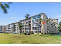 A condo with large windows, a well-manicured lawn, and palm trees on a sunny day at 3664 Lake Bayshore Dr # K323, Bradenton, FL 34205