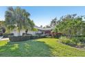 Wide shot of a landscaped property featuring a well-maintained lawn, trimmed shrubbery, and mature palm trees at 3880 Wilshire Cir # 28, Sarasota, FL 34238