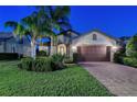 Charming single-Gathering home featuring a well-manicured lawn, lush landscaping, and warm exterior lights at 5361 Sundew Dr, Sarasota, FL 34238