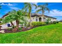 Charming single-story home featuring lush landscaping, mature palms, and a well-manicured lawn under a bright blue sky at 16111 Sunny Day Dr, Bradenton, FL 34211